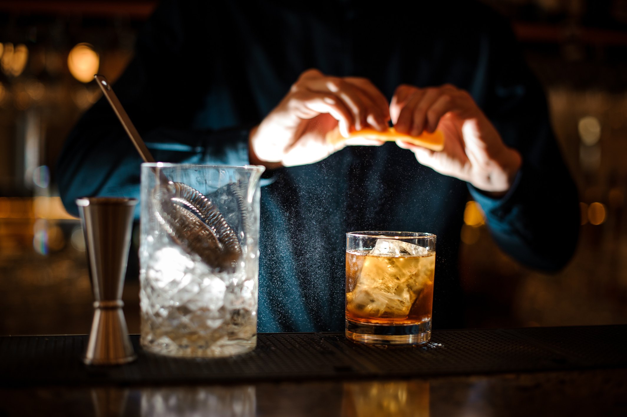 barman finishes preparing an alcoholic cocktail Old Fashioned adding an orange bitter